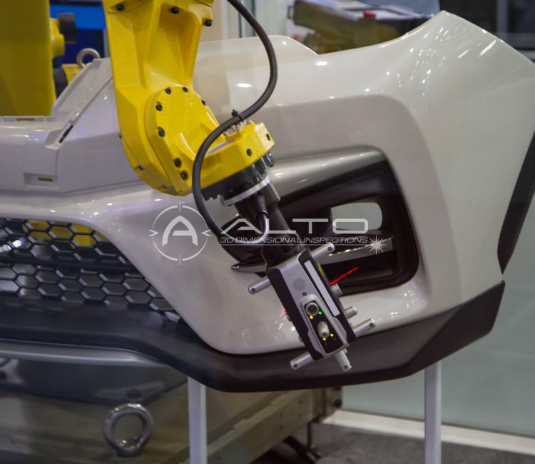 A yellow robotic arm works on a white car bumper, using precise tools such as the Leica AT960 for assembly or inspection in an industrial or automotive manufacturing setting.