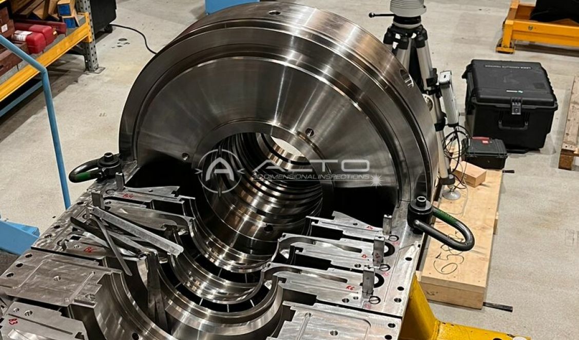 A Leica Absolute Tracker AT960 positioned on a tripod behind a large machined turbine diaphragm for real-time alignment verification.